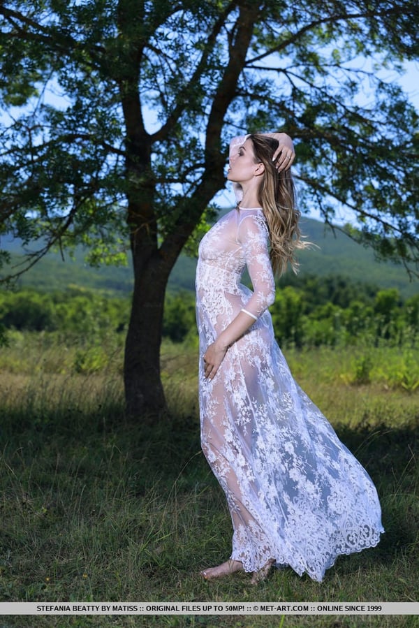 Picture by glambabes-galleries showing 'Hot teen Stefania Beatty slips out of a sheer dress to pose naked in a field' number 17