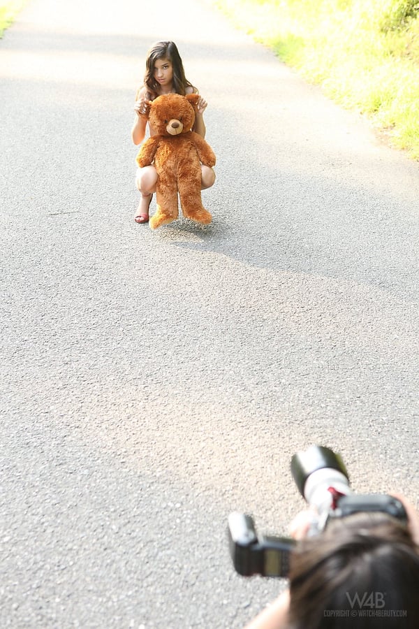 Young looking teen Nika poses naked on a road with a stuffed bear