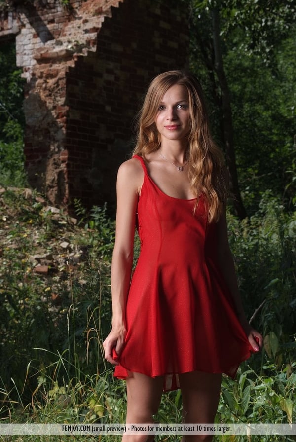 Thin girl takes off her red dress in nature to pose her hot body in the nude