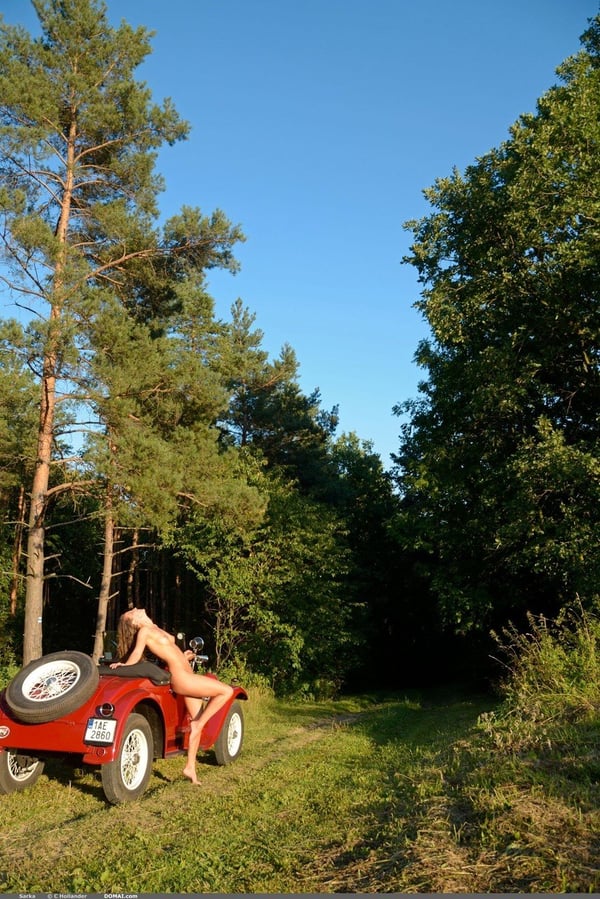Picture by glambabes-galleries showing 'White solo girl poses naked in and on a vintage roadster out among the trees' number 13