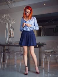 Geeky redhead Elin Flame fingers her shaved teen pussy on a dining chair