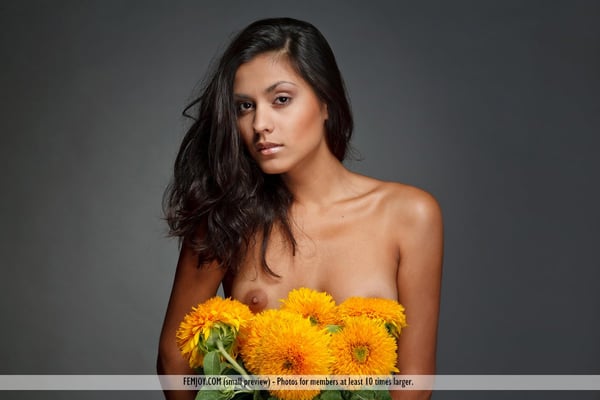 Brunette solo girl puts down a bunch of flowers while modeling in the nude