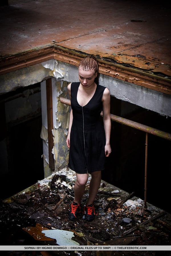 Slender teen Sophia I stands naked after disrobing in an abandoned building