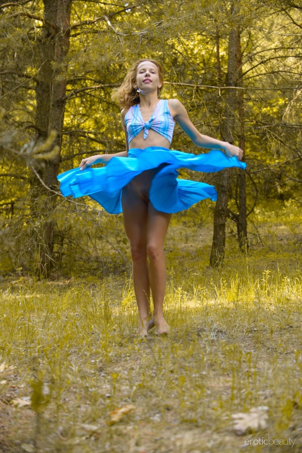 Caucasian model poses her skinny body in a clearing in the forest